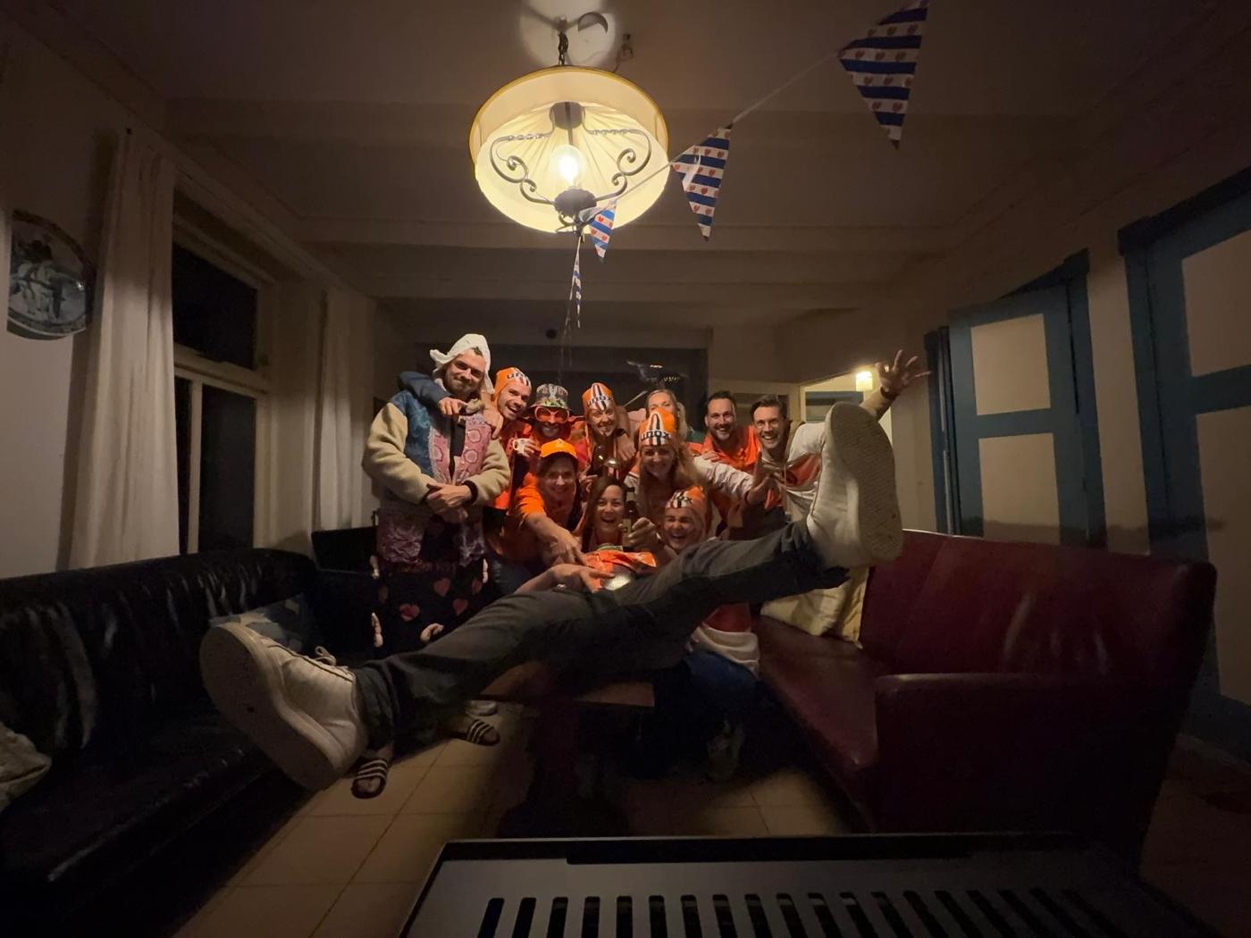De vriendengroep in het oranje, samen op de bank onder een Friese vlaggenlijn